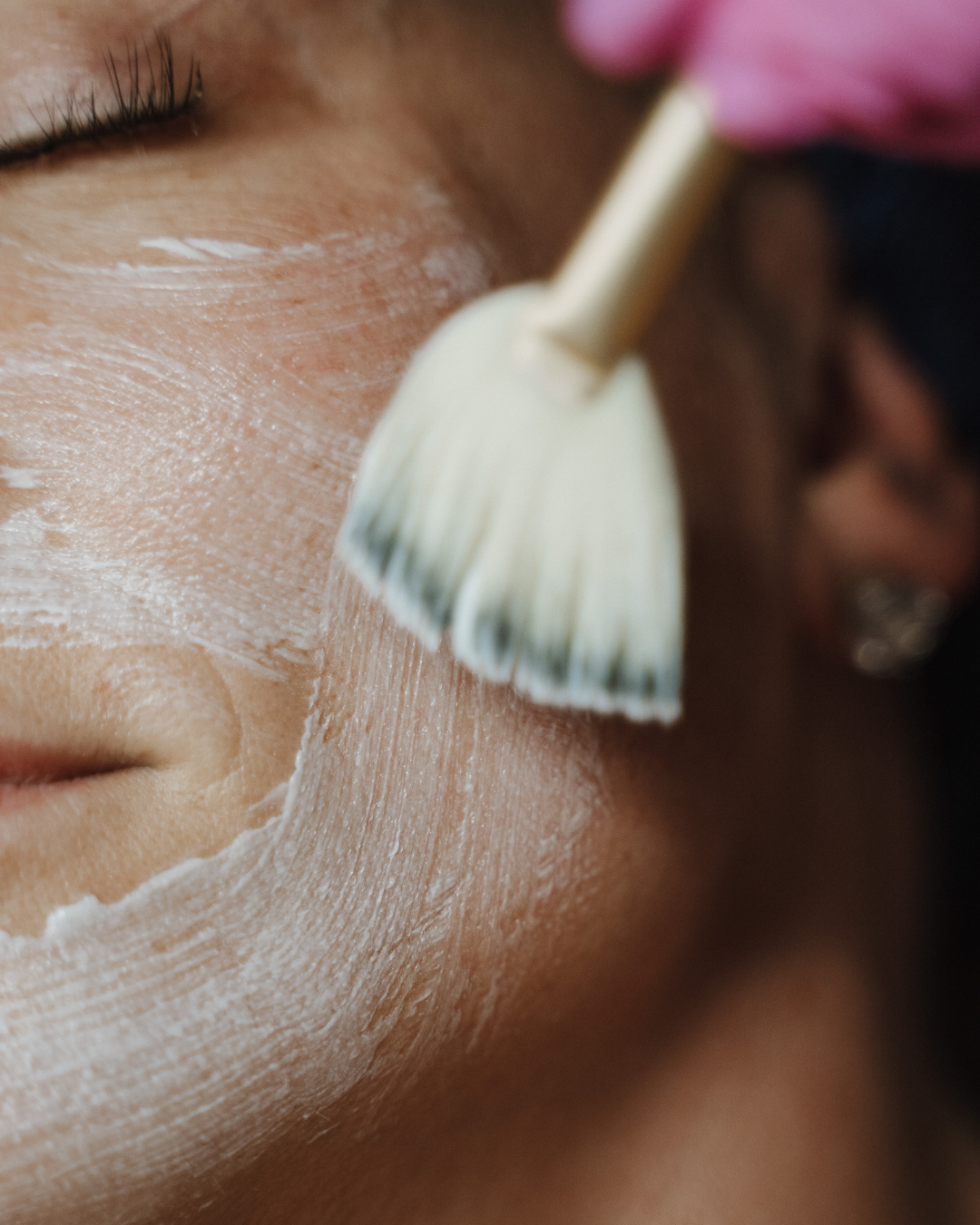 Applying facial mask with brush on skin.