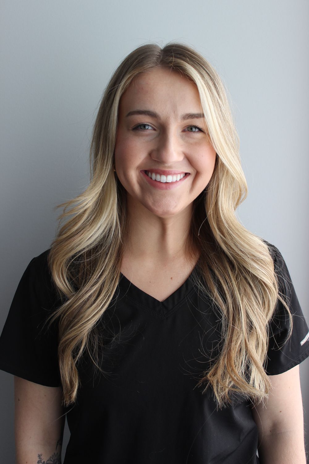 Smiling person wearing a black medical uniform.
